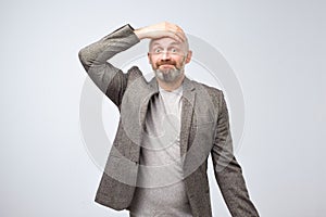 Closeup portrait of a man holding his hand on head, staring thoughtfully at camera