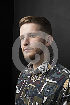 Closeup portrait of a man in shirt - posing at studio, with fashion hairstyle. Adult with brown hair, black background.