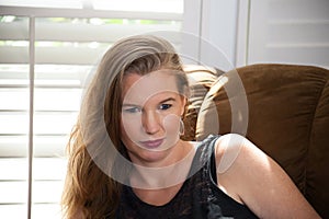 Closeup Portrait Mature Blonde Female Sitting on Sofa Looking Away From Camera