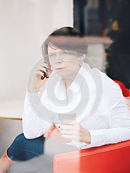 Closeup portrait of middle age Caucasian white business woman sitting in cafe restaurant with cup of coffee talking over on phone