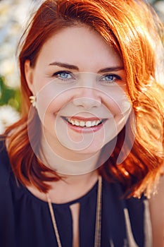 Closeup portrait of middle aged white caucasian woman with waved curly red hair in black dress looking in camera