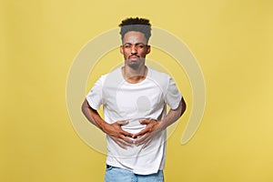 Closeup portrait of miserable, upset, young man, doubling over in stomach pain, looking very sick unwell, isolated on