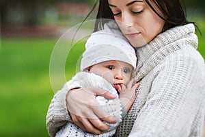 Closeup portrait of mom holding baby outdoors at park background. Concept of happy family