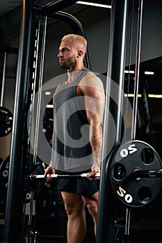 Closeup portrait of a muscular man workout with barbell at gym. Brutal bodybuilder athletic man with six pack, perfect