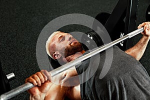 Closeup portrait of a muscular man workout with barbell at gym. Brutal bodybuilder athletic man with six pack, perfect