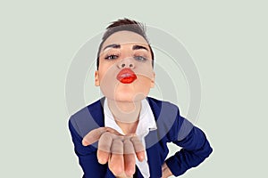 Closeup portrait of nerdy young funny distorted woman face with big red lips blowing sending  a kiss to you camera, isolated light