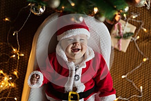 Closeup portrait of newborn baby. Cute Caucasian baby girl 4-5 months old in Santa costume lying on knitted cozy blanket