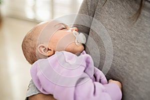 Closeup portrait of a newborn baby sleeping in mother's arms