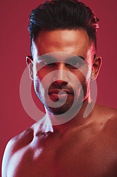 Closeup portrait of one fit and strong handsome mixed race man isolated against a red background in a studio and posing