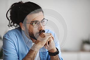 Closeup Portrait Of Pensive Millennial Indian Man In Eyeglasses Looking Away photo