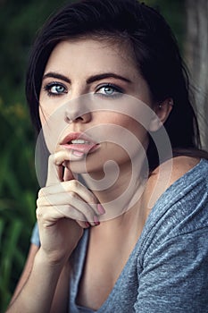 Closeup portrait of pensive thoughtful beautiful young Caucasian woman with black hair, blue eyes, looking in camera