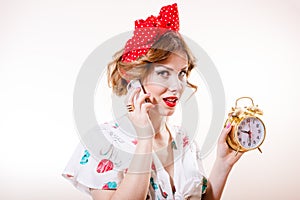 Closeup portrait of pinup woman with alarm clock on the phone