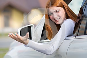 Closeup portrait of pissed off displeased angry aggressive woman driving a car shouting at someone with hand up. Negative human