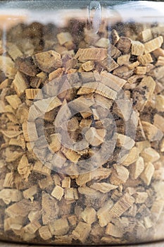 A closeup portrait of a plastic pot or jar full of fresh glycyrrhiza glabra liquorice pieces to set a fresh cup of tea. The herbs