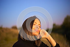 Closeup portrait of a pleased relaxed woman with closed eyes holding hand under chin