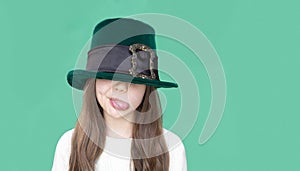 A closeup portrait of preteen girl in St. Patrick& x27;s Day hat on green backgroundwhite. Copy space