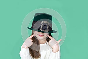 A closeup portrait of preteen girl in St. Patrick& x27;s Day hat on green backgroundwhite. Copy space