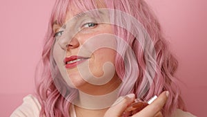 Closeup portrait of pretty young female with bottle of perfume and applying it. Beautiful girl using perfume over bright