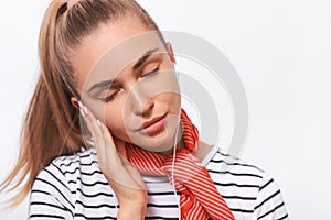 Closeup portrait of pretty young woman wearing striped t-shirt, stylish red scarf on neck, relaxing with closed eyes listening to