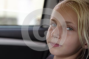 Closeup portrait of a relaxed and calm car passenger. A beautiful young blond girl is enjoying the journey in the car. Copy space