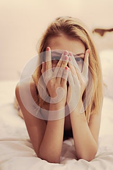 Closeup portrait of romantic blond seductive young woman lying in bed