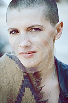 Closeup portrait of sad beautiful Caucasian white young bald girl woman with shaved hair head in leather jacket and scarf