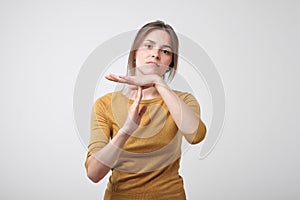 Closeup portrait of sad stressed woman showing time out gesture with hands isolated on gray wall background.