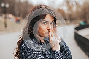 Closeup portrait secretive young woman placing finger on lips