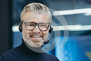Closeup portrait of senior mature boss with headset, video call, man smiling and looking at camera, gray haired