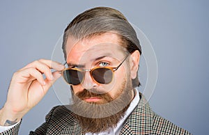 Closeup portrait of serious attractive man takes off sunglasses. Handsome bearded man in suit taking-off his eyeglasses
