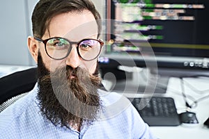 Closeup portrait of a serious computer programmer developer working in IT office, sitting at desk and coding a project