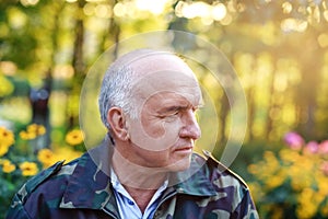 Closeup portrait of an serious elegant senior man thinking about something at the garden