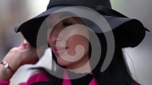 Closeup portrait of sexy woman with tattoo brows and lips, walking on street, black hat on head