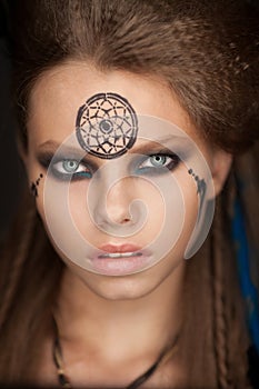 Closeup portrait of shamanic female with colorful makeup.