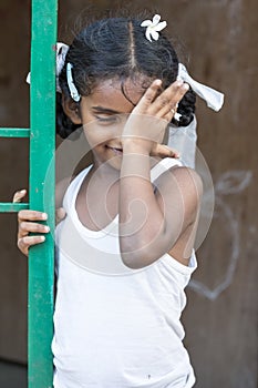 Closeup portrait of shy timid young pretty Indian girl child looking away and covering eye. Shy concept.