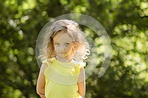 Closeup portrait of a skeptical little girl looking suspiciously, skeptical, half-smile, ironically. Portrait in green