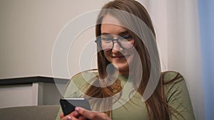 Closeup. Portrait of smiling attractive young woman in glasses use phone for online shopping in social media sit on