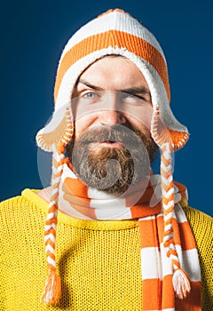 Closeup portrait of smiling bearded man in striped scarf and hat. Winter accessories. Handsome man with beard and