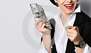 Closeup portrait of smiling business woman managing director holding fan of dollars banknotes and pointing finger at us