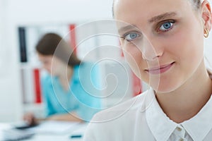 Closeup portrait of smiling businesswoman with female colleague on the background. Serious business and partnership, job