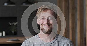 Closeup portrait of smiling European blonde guy posing at luxury apartment loft interior