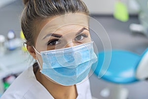 Closeup portrait of smiling female dentist doctor in protective medical mask