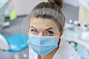 Closeup portrait of smiling female dentist doctor in protective medical mask