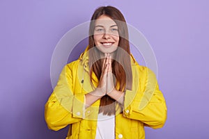 Closeup portrait of smiling female with palms together, standing and praying, lady looks hopeful, winsome woman poses smiling