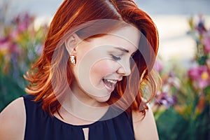 Closeup portrait of smiling laughing flirty middle aged white caucasian woman with waved curly red hair in black dress