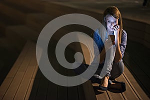 Closeup portrait smiling or laughing young freelancer woman looking at phone seeing good news or photos with nice emotion