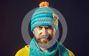 Closeup portrait of smiling man with beard in hat and scarf. Winter accessories. Handsome bearded man in yellow sweater