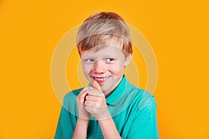 Closeup portrait of sneaky sly scheming kid boy on yellow background
