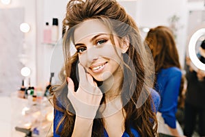 Closeup portrait stylish cute young woman with long brunette hair smiling to camera in hairdresser salon. Beauty