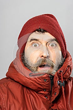 Closeup portrait of surprised man in winter coat freezing in the cold